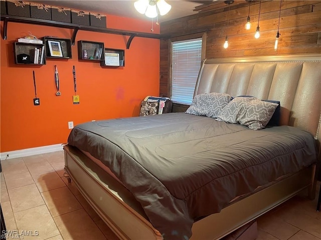 bedroom with wood walls and light tile patterned floors