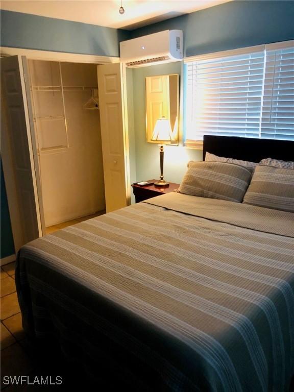 bedroom with tile patterned flooring, a closet, and an AC wall unit