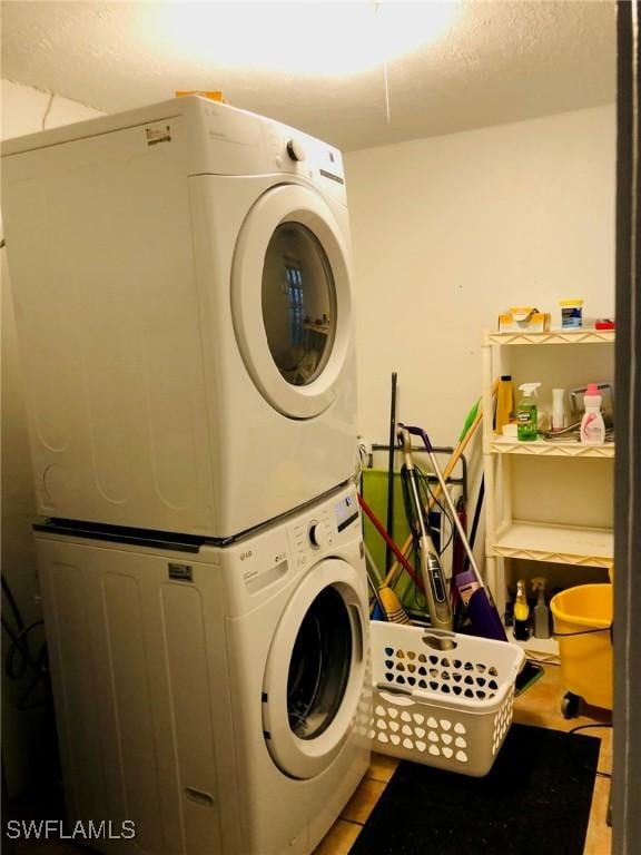 washroom with stacked washer / drying machine and light tile patterned floors