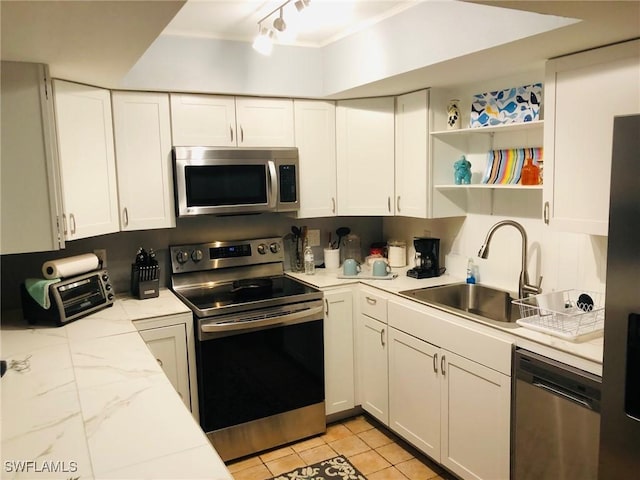 kitchen featuring white cabinetry, appliances with stainless steel finishes, sink, and light tile patterned floors