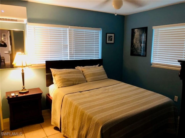 bedroom featuring a wall mounted air conditioner, light tile patterned floors, and ceiling fan