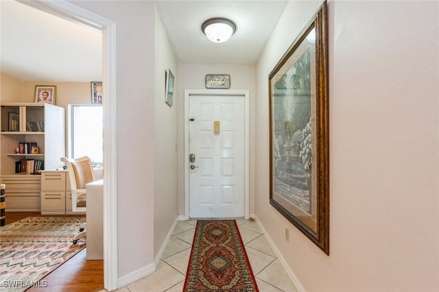 doorway to outside featuring light tile patterned flooring and baseboards
