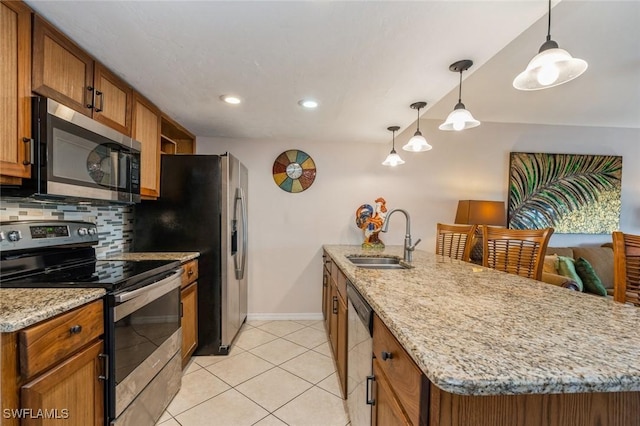 kitchen featuring a sink, appliances with stainless steel finishes, baseboards, a peninsula, and brown cabinetry