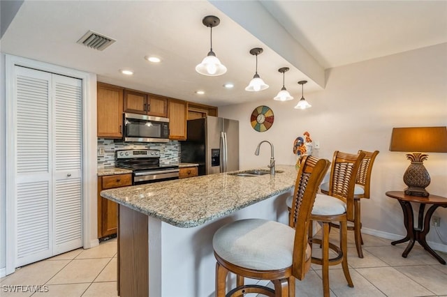kitchen with brown cabinetry, stainless steel appliances, light tile patterned floors, a sink, and visible vents