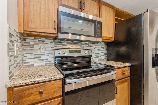 kitchen featuring tile patterned floors, stainless steel appliances, light stone countertops, and backsplash