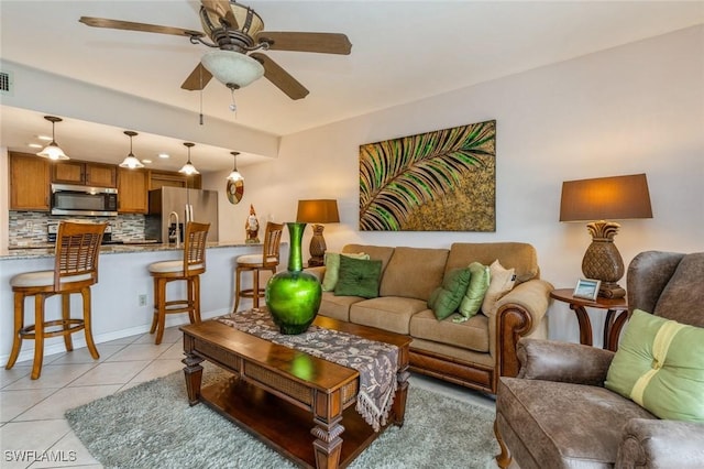 living room with light tile patterned floors, visible vents, a ceiling fan, and baseboards