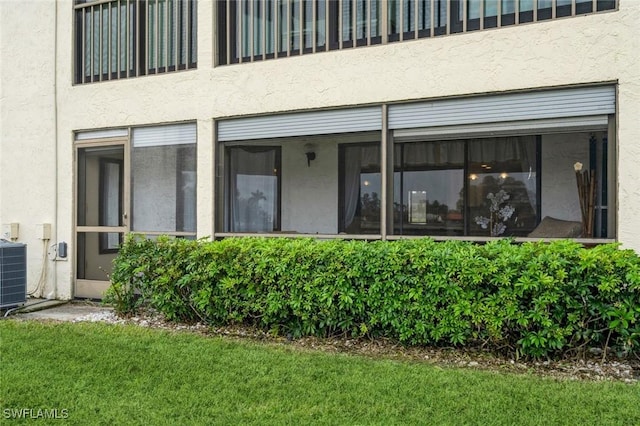 rear view of property with a lawn and cooling unit