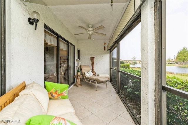 sunroom / solarium with ceiling fan and a water view