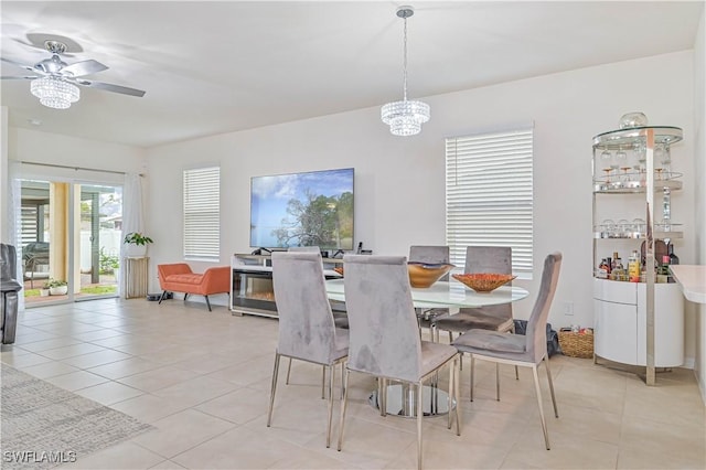 dining space with light tile patterned flooring and ceiling fan with notable chandelier