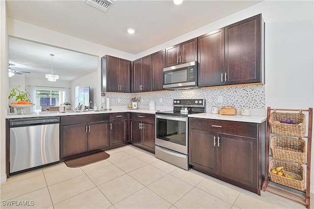 kitchen with hanging light fixtures, tasteful backsplash, appliances with stainless steel finishes, and dark brown cabinets