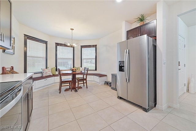 kitchen featuring appliances with stainless steel finishes, hanging light fixtures, dark brown cabinetry, light tile patterned flooring, and a chandelier