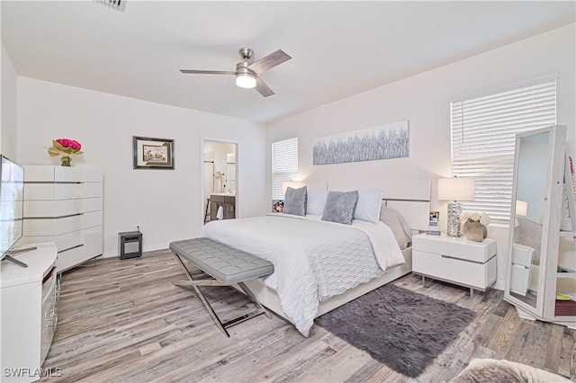 bedroom with light wood-type flooring, ceiling fan, and ensuite bathroom