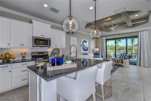 kitchen with a center island with sink, stainless steel appliances, beamed ceiling, and coffered ceiling