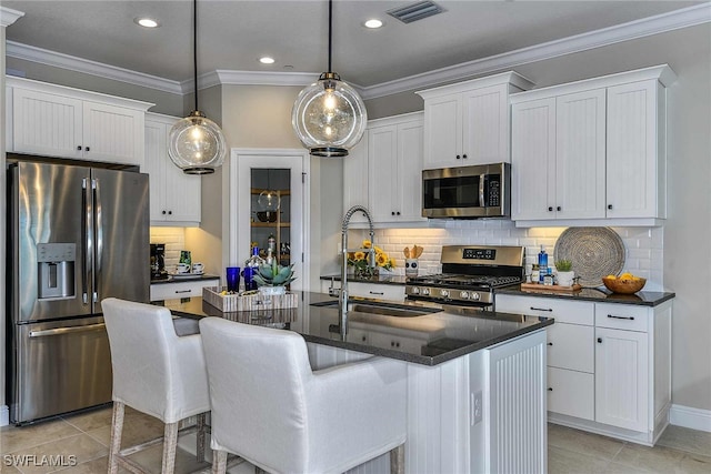 kitchen with an island with sink, white cabinets, pendant lighting, and stainless steel appliances