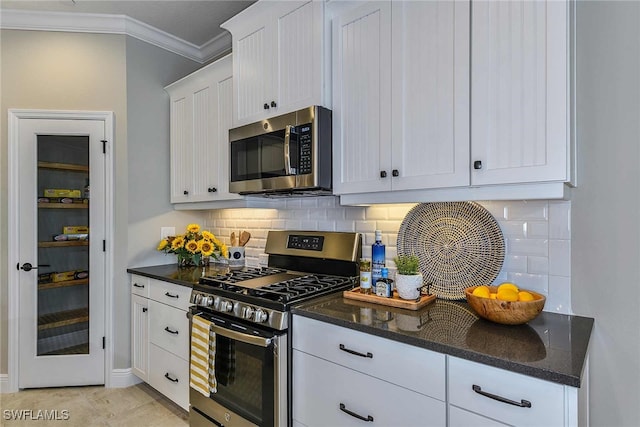 kitchen with crown molding, decorative backsplash, white cabinets, dark stone countertops, and stainless steel appliances