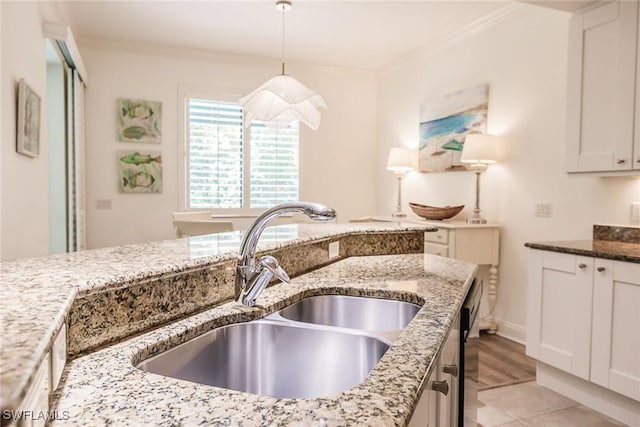 kitchen featuring light stone counters, sink, pendant lighting, and ornamental molding