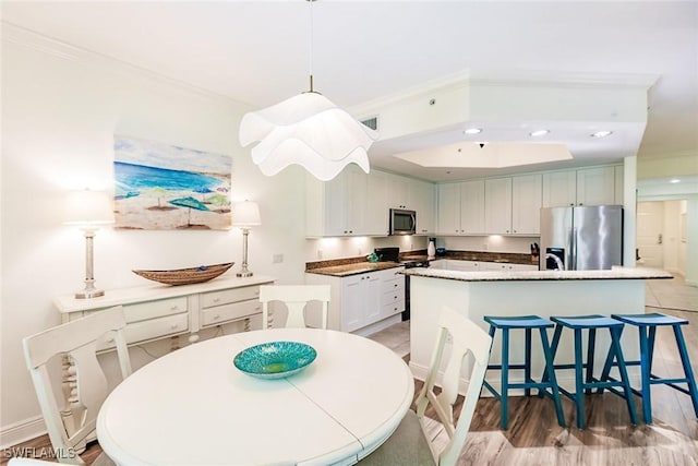 kitchen featuring crown molding, white cabinetry, decorative light fixtures, an island with sink, and stainless steel appliances