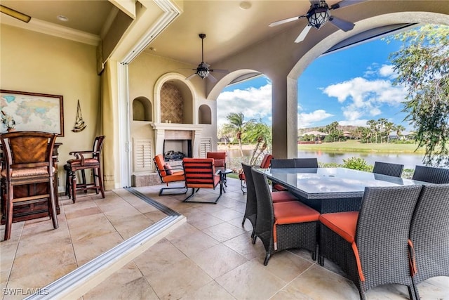 view of patio featuring outdoor dining area, a water view, a fireplace, and ceiling fan