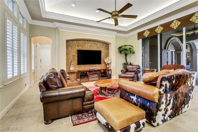 living room featuring ornamental molding, arched walkways, and a raised ceiling