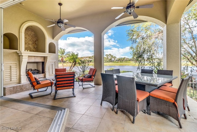 view of patio / terrace featuring a water view, exterior fireplace, and outdoor dining space