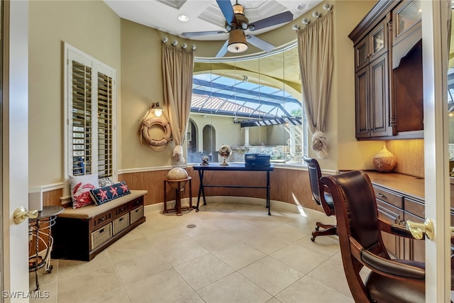 office space featuring light tile patterned flooring, wood walls, wainscoting, and a ceiling fan