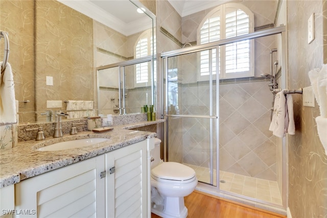 full bathroom featuring toilet, ornamental molding, a stall shower, vanity, and wood finished floors