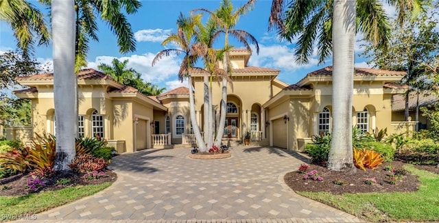 mediterranean / spanish-style home featuring decorative driveway, an attached garage, and stucco siding