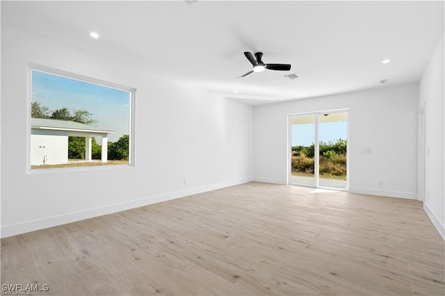 spare room featuring ceiling fan, light wood-type flooring, and plenty of natural light