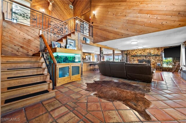 unfurnished living room with a healthy amount of sunlight, wooden walls, a fireplace, and a towering ceiling