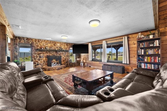 living room with tile patterned floors, a stone fireplace, a textured ceiling, radiator heating unit, and wooden walls