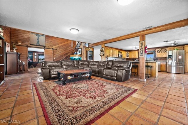 tiled living room featuring wooden walls, a barn door, and a textured ceiling