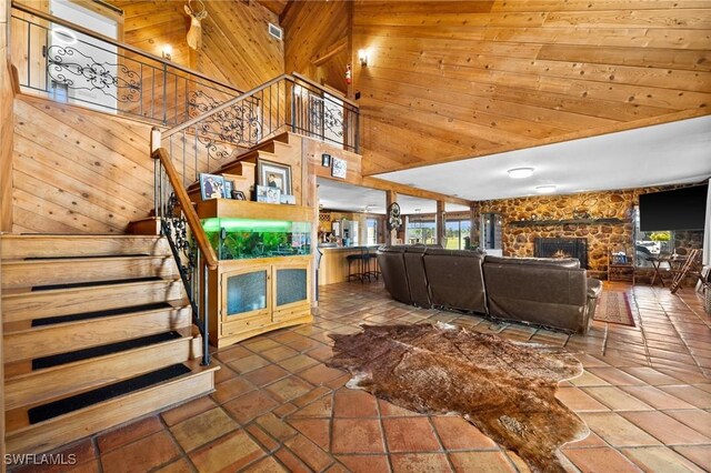 unfurnished living room featuring a towering ceiling, wooden walls, and a fireplace