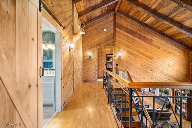 hall with wood ceiling, beam ceiling, and wood walls