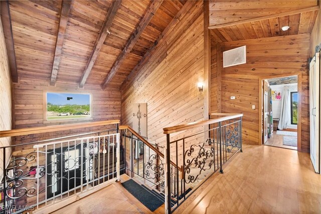 hallway with vaulted ceiling with beams, wood ceiling, wooden walls, and wood-type flooring