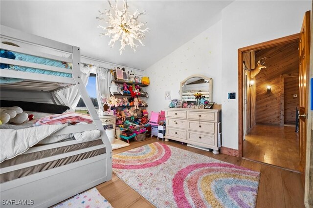 bedroom featuring an inviting chandelier, vaulted ceiling, and light hardwood / wood-style flooring