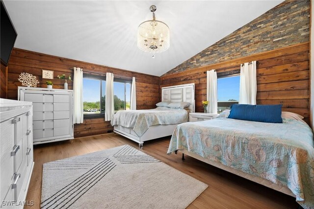 bedroom featuring hardwood / wood-style floors, a notable chandelier, vaulted ceiling, and wood walls