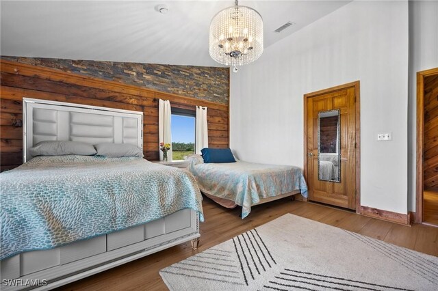 bedroom with hardwood / wood-style flooring, lofted ceiling, and a chandelier