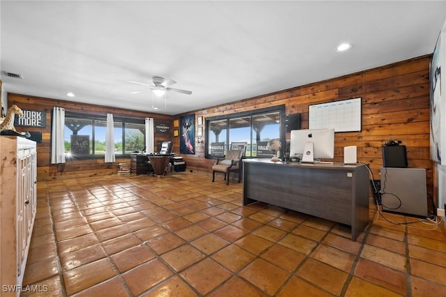 living room with tile patterned flooring, ceiling fan, and wood walls