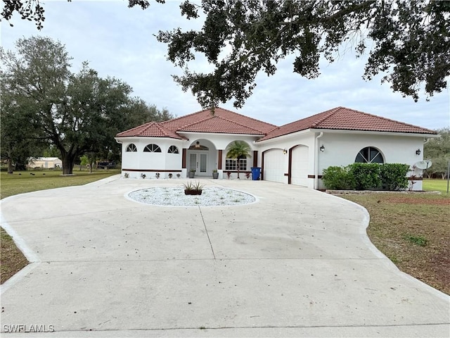 mediterranean / spanish-style house featuring a garage and a front yard