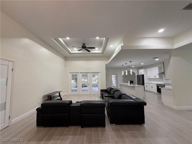 living room with ceiling fan, sink, and a tray ceiling