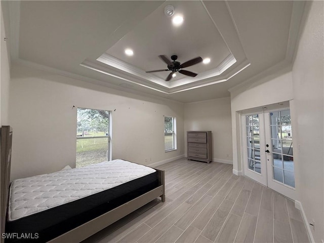 bedroom featuring ceiling fan, access to exterior, multiple windows, and a tray ceiling