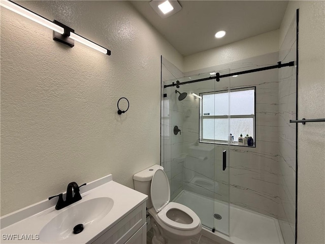 bathroom featuring a shower with shower door, toilet, and vanity