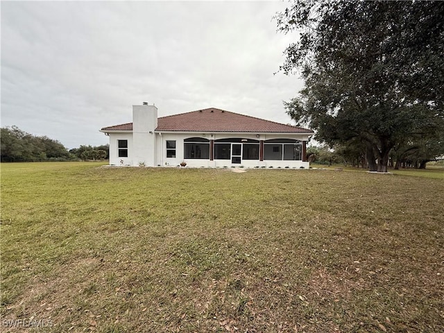 rear view of house with a yard and a sunroom