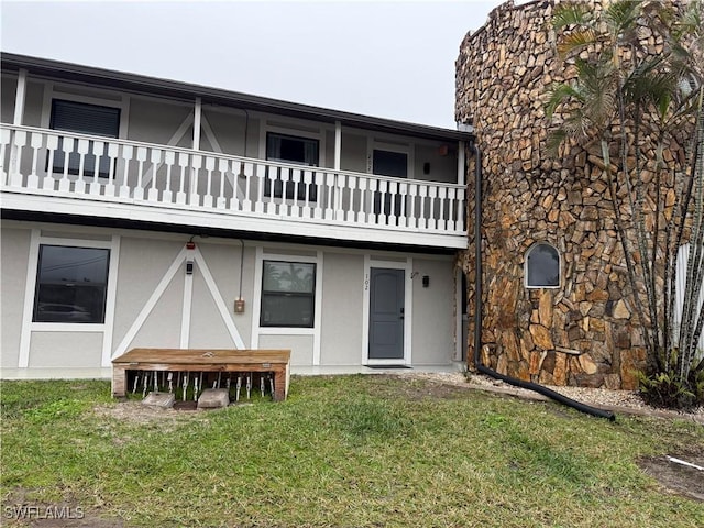 back of property with a balcony and a yard