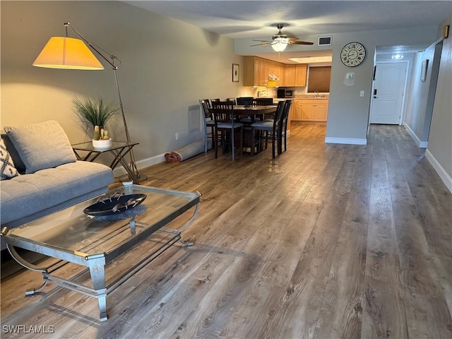 living room featuring ceiling fan, sink, and hardwood / wood-style floors