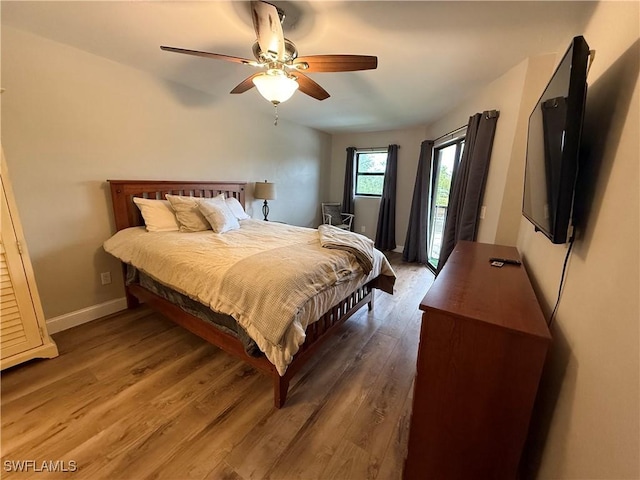 bedroom with ceiling fan, dark hardwood / wood-style floors, and access to exterior