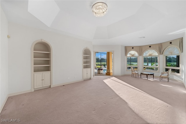 interior space featuring built in features, a raised ceiling, plenty of natural light, and light carpet