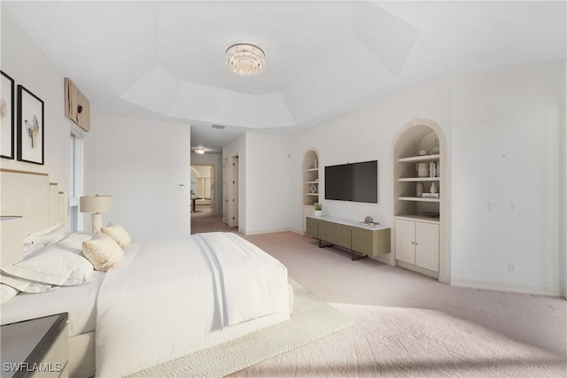 carpeted bedroom with a tray ceiling and a chandelier