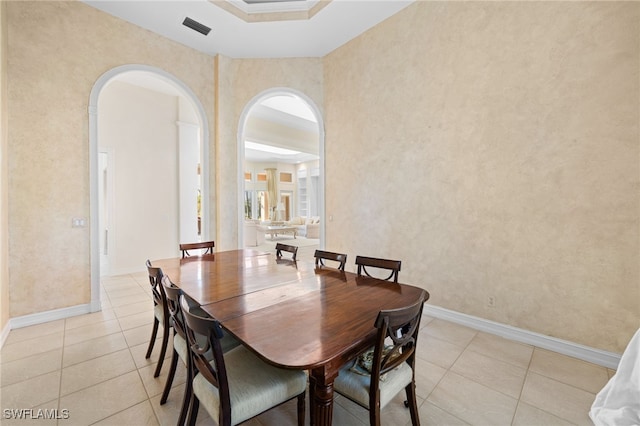 dining space featuring ornamental molding, a raised ceiling, and light tile patterned flooring