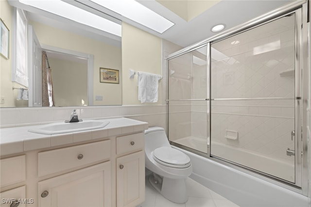 full bathroom with toilet, combined bath / shower with glass door, tile walls, tile patterned flooring, and vanity